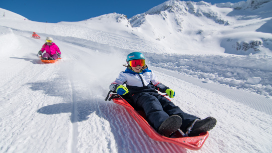 Family sledging in Val Thorens on the Cosmojet toboggan run, in Les 3 Vallées